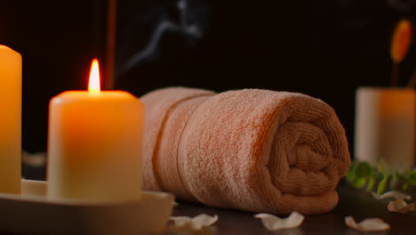 Still-Life-Of-Lit-Candles-With-Scattered-Petals-Incense-Stick-And-Soft-Towels-Against-Dark-Background-As-Part-Of-Relaxing-Spa-Day-Decor-2